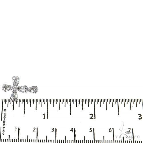White gold baguette diamond cross pendant next to ruler showing size under 1 inch