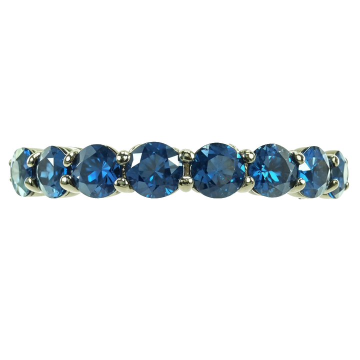 Blue sapphire gemstone ring in polished white metal with round stones set in a row.
