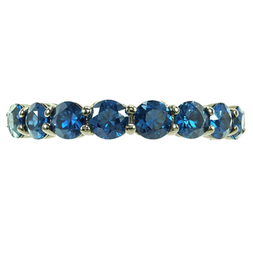 Blue sapphire gemstone ring in polished white metal with round stones set in a row.