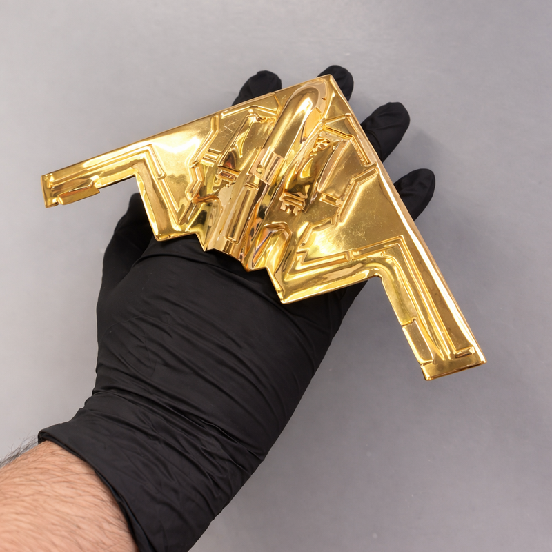 Polished gold four-finger ring shaped like a B-2 bomber aircraft held by hand.