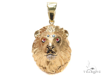 Yellow gold lion head pendant with ruby eyes and detailed mane engraving.
