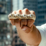 Gold knuckle ring with four large round diamonds and pavé diamond accents on top.