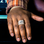 Yellow gold men's ring with large center diamond and multiple surrounding diamonds.