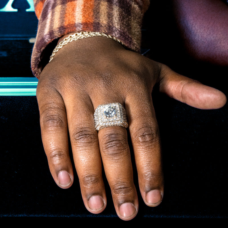 Yellow gold men's ring with large center diamond and multiple surrounding diamonds.
