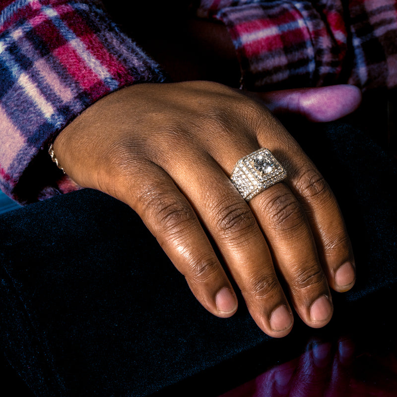 Yellow gold men's ring with large center diamond and multiple surrounding diamonds.
