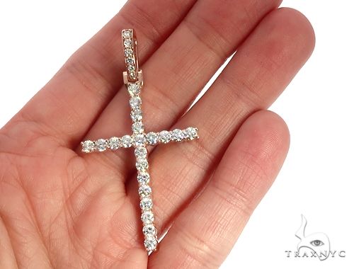 14K rose gold cross pendant with prong-set round diamonds held in hand