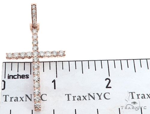 14K rose gold cross pendant with prong-set round diamonds, shown next to ruler for scale
