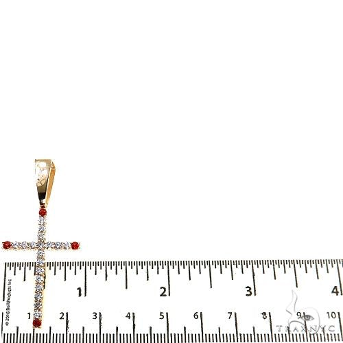 Men's diamond cross pendant with red gemstones, shown next to ruler for size reference