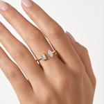 Gold open ring with two differently shaped diamonds on each end, worn on hand.