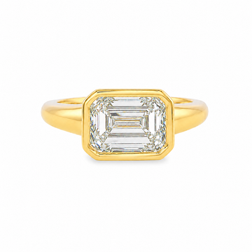 Yellow gold ring with emerald-cut diamond in a bezel setting.
