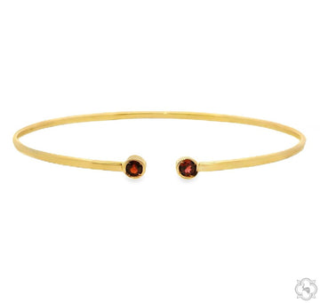 polished gold open bangle bracelet with two red gemstones at open terminals, front angle