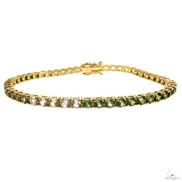Yellow gold tennis bracelet with alternating green sapphires and white gemstones.