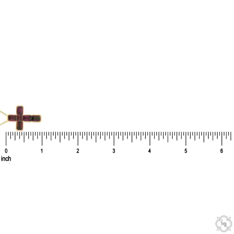 Small rose gold cross pendant with garnet gemstones, shown next to inch ruler for size reference