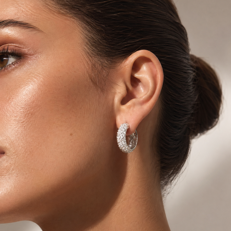 Silver hoop earrings with an inverted mosaic diamond pattern, sparkling design on model's ear.