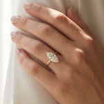 Gold band engagement ring with marquise-cut diamond solitaire on woman's hand.