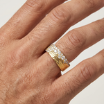 Wide gold wedding band with hammered texture and a row of small diamonds across the center.