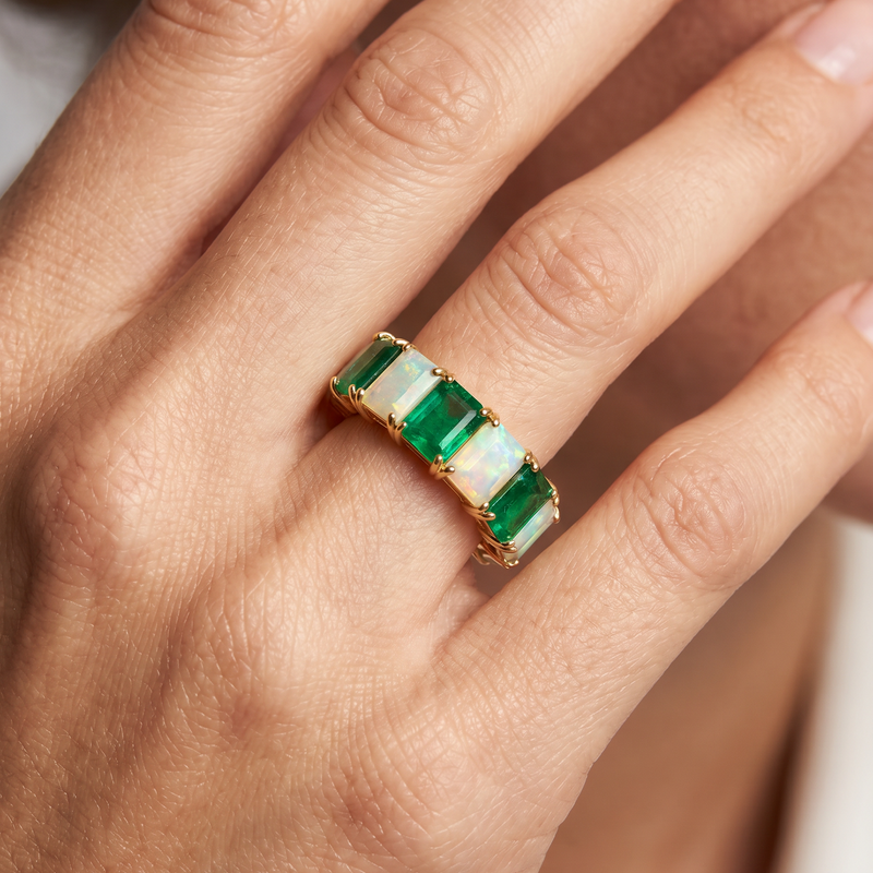 Yellow gold eternity ring with alternating rectangular emerald and opal gemstones.