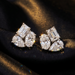White gold earrings with trio cluster of emerald, oval, and pear-shaped diamonds.