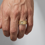Gold men's spinner ring with diamond accents and textured mechanical design.