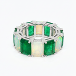 Silver eternity ring with alternating square emerald and opal gemstones.