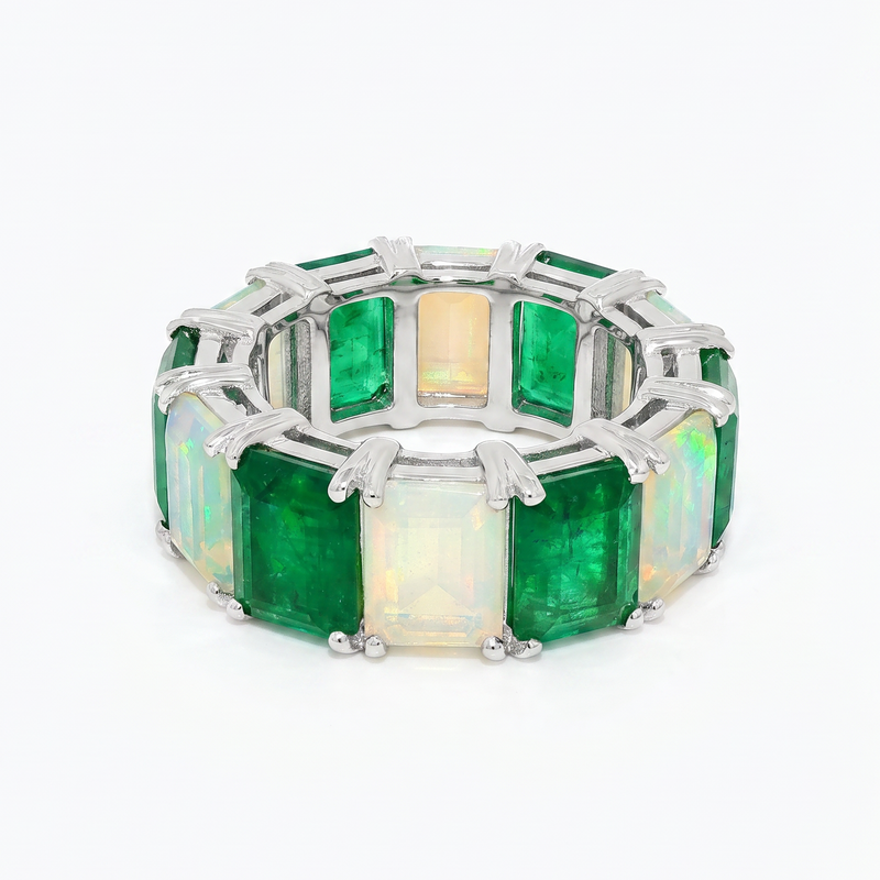 Silver eternity ring with alternating square emerald and opal gemstones.