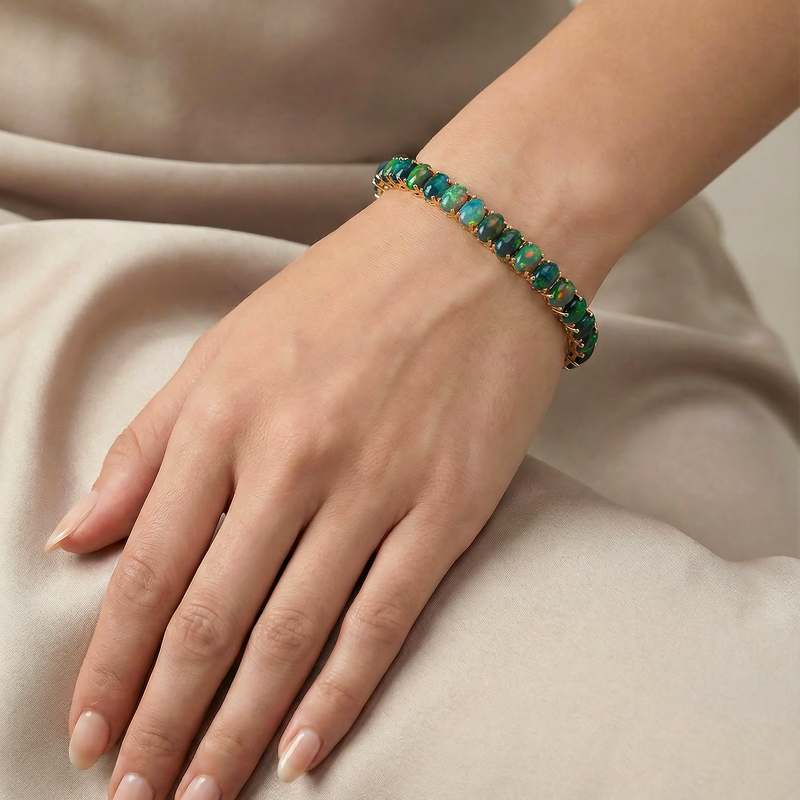 Gold tennis bracelet with oval galaxy black opal gemstones on wrist.