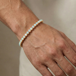 Gold tennis bracelet with oval opal gemstones, polished finish, unisex design.