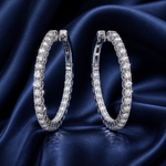 White gold inside-out diamond hoop earrings on dark blue satin background.