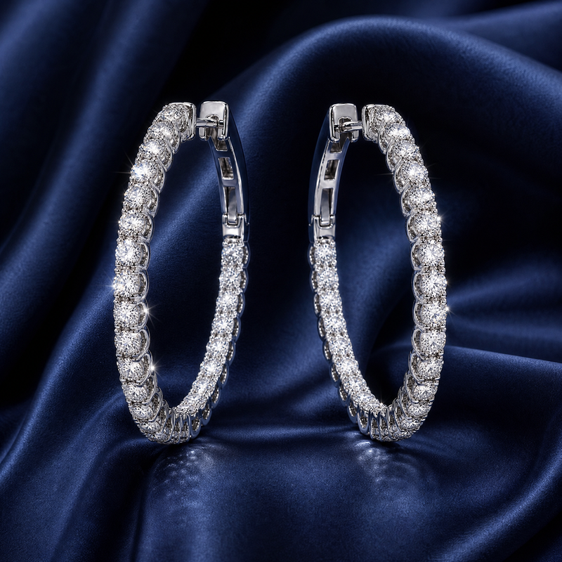 White gold inside-out diamond hoop earrings on dark blue satin background.