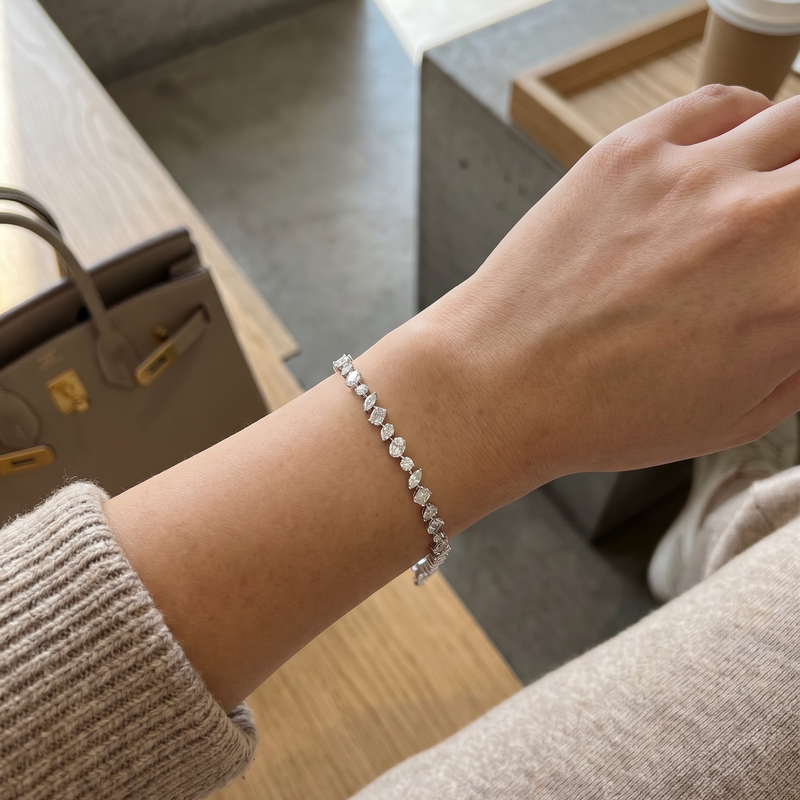 Silver bracelet with alternating round and marquise diamonds on a wrist.