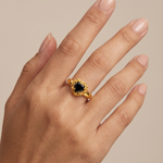 Gold heart-shaped black diamond ring with ornate floral filigree gold frame and prong setting
