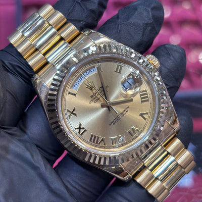 Rolex Day-Date 40mm in 18K yellow gold with a champagne Roman dial and fluted bezel, front view.