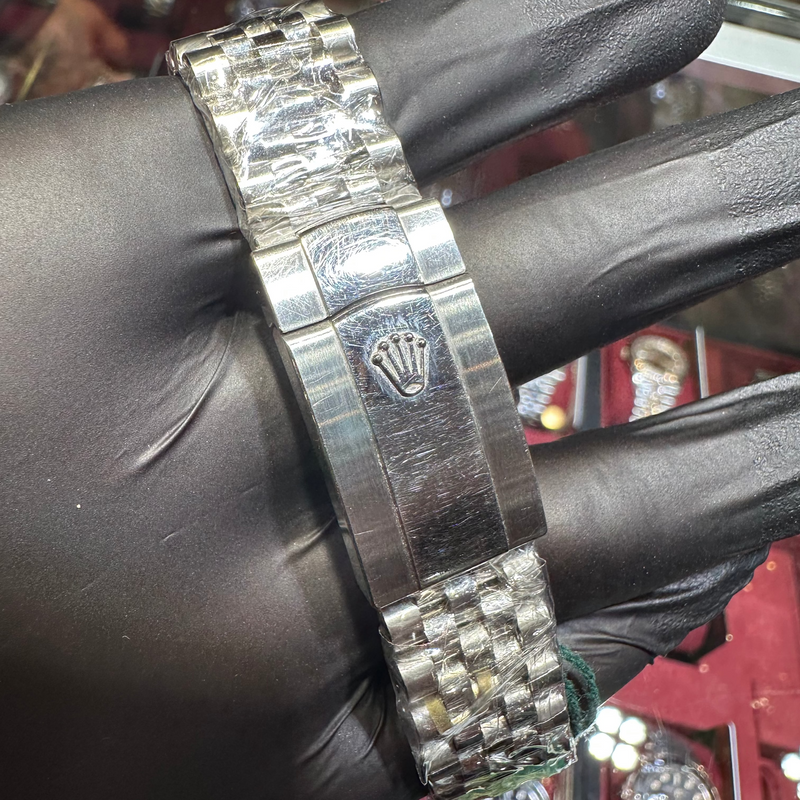 Silver watch with Rolex logo on a black gloved hand against a blurred background
