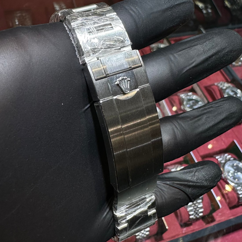 Hand wearing a silver watch with a display of watches in the background