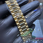 Gold watch bracelet held by a gloved hand with a blurred background
