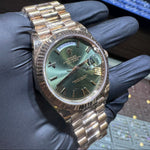 Gold watch band held by a gloved hand with a blurred background