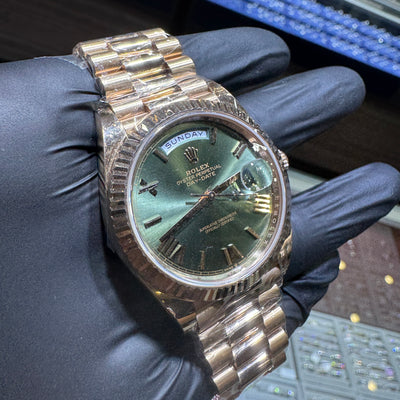 Gold watch band held by a gloved hand with a blurred background