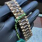 Gold watch band held by a gloved hand with a blurred background