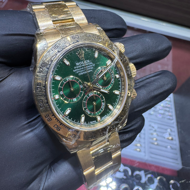 Gold watch with a green face held by a gloved hand