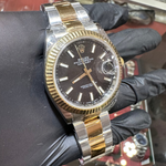 Rolex watch with gold and silver band held by a gloved hand