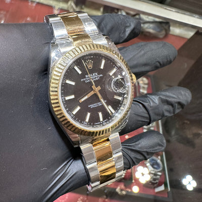 Rolex watch with gold and silver band held by a gloved hand