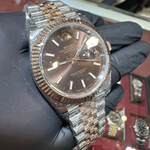 Luxury watch with a metallic band held by a gloved hand against a blurred background