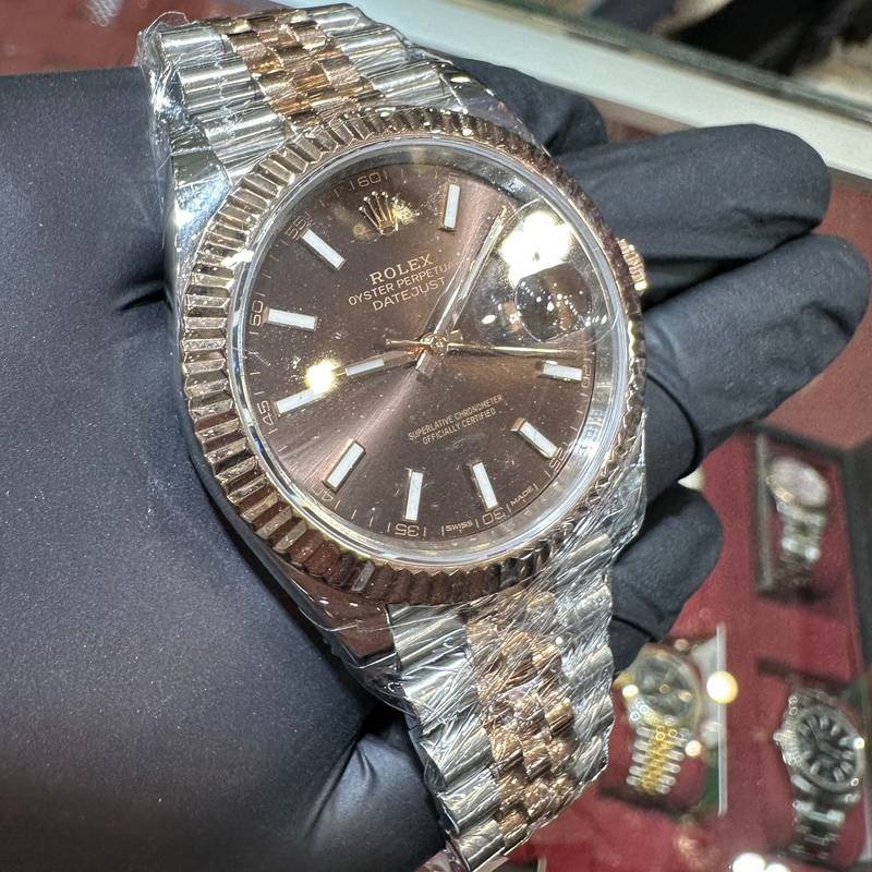 Luxury watch with a metallic band held by a gloved hand against a blurred background
