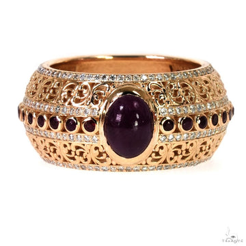 Rose gold ring with central oval ruby, smaller round rubies, and intricate filigree detailing.