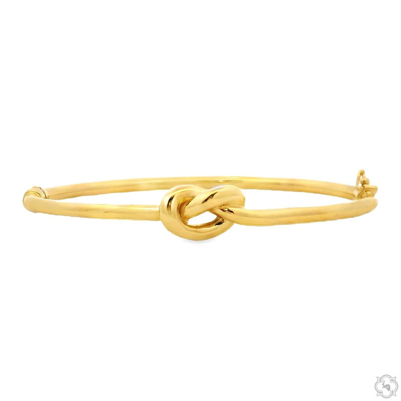 Yellow gold bangle bracelet with a polished finish and a central knot detail