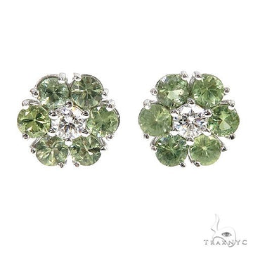 White gold cluster earrings with green sapphires and central diamond floral design.