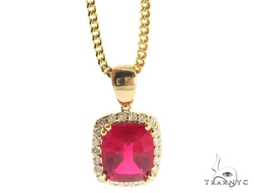 Yellow gold chain with cushion-cut red gemstone pendant surrounded by small diamonds.