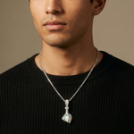 Man wearing a black sweater with a silver necklace featuring a pendant.