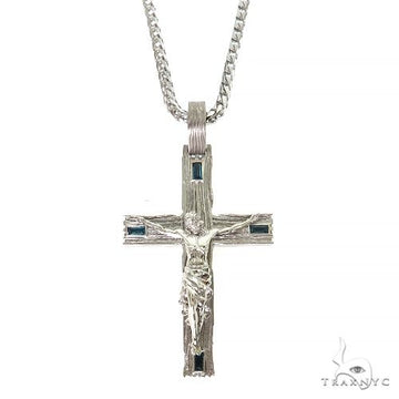Silver cross pendant with dark blue gemstones and detailed crucifix on silver chain.