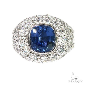 Men's yellow gold ring with cushion-cut sapphire surrounded by multiple diamonds.